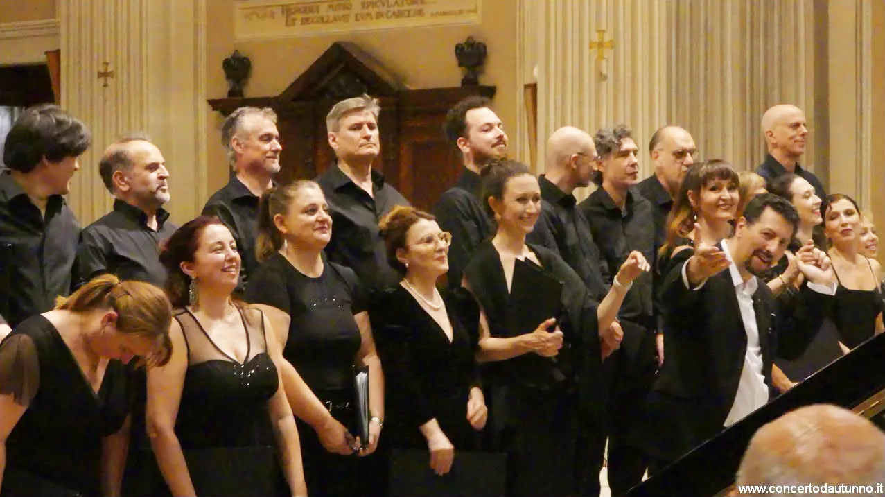 Coristi e coriste sorridenti salutano il pubblico al termine del concerto